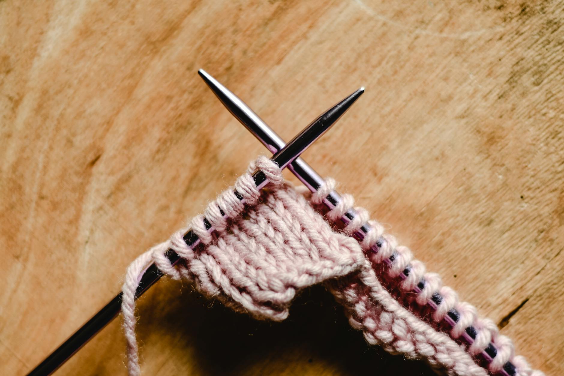 close up of a knitting needles on a wooden surface